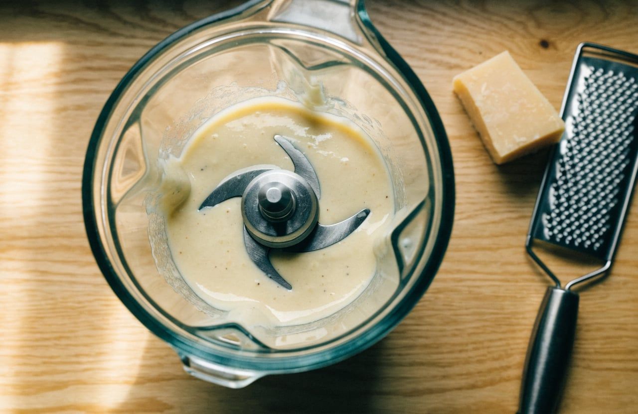 Blender jar of smooth ivory cottage cheese and parmesan sauce with no visible curds