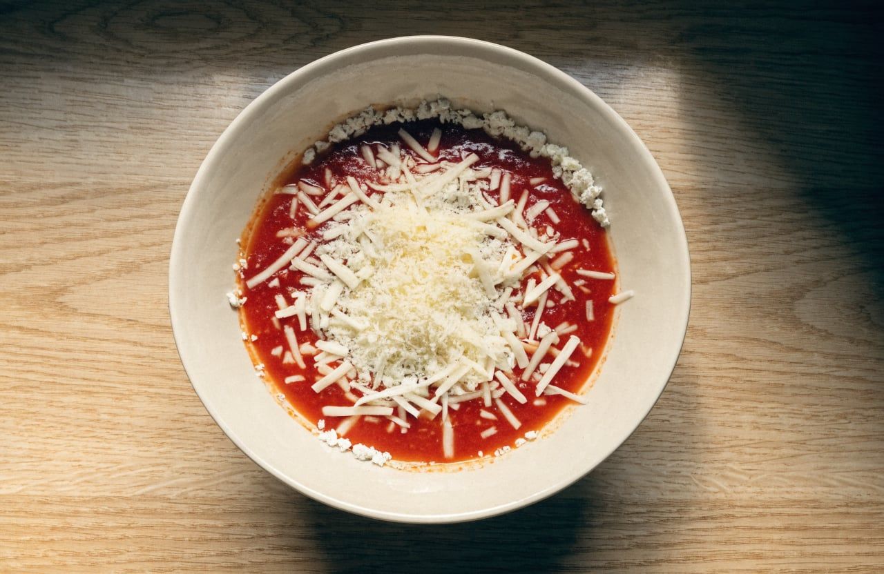 Bowl with marinara spread over cottage cheese, topped with unmelted shredded mozzarella and parmesan