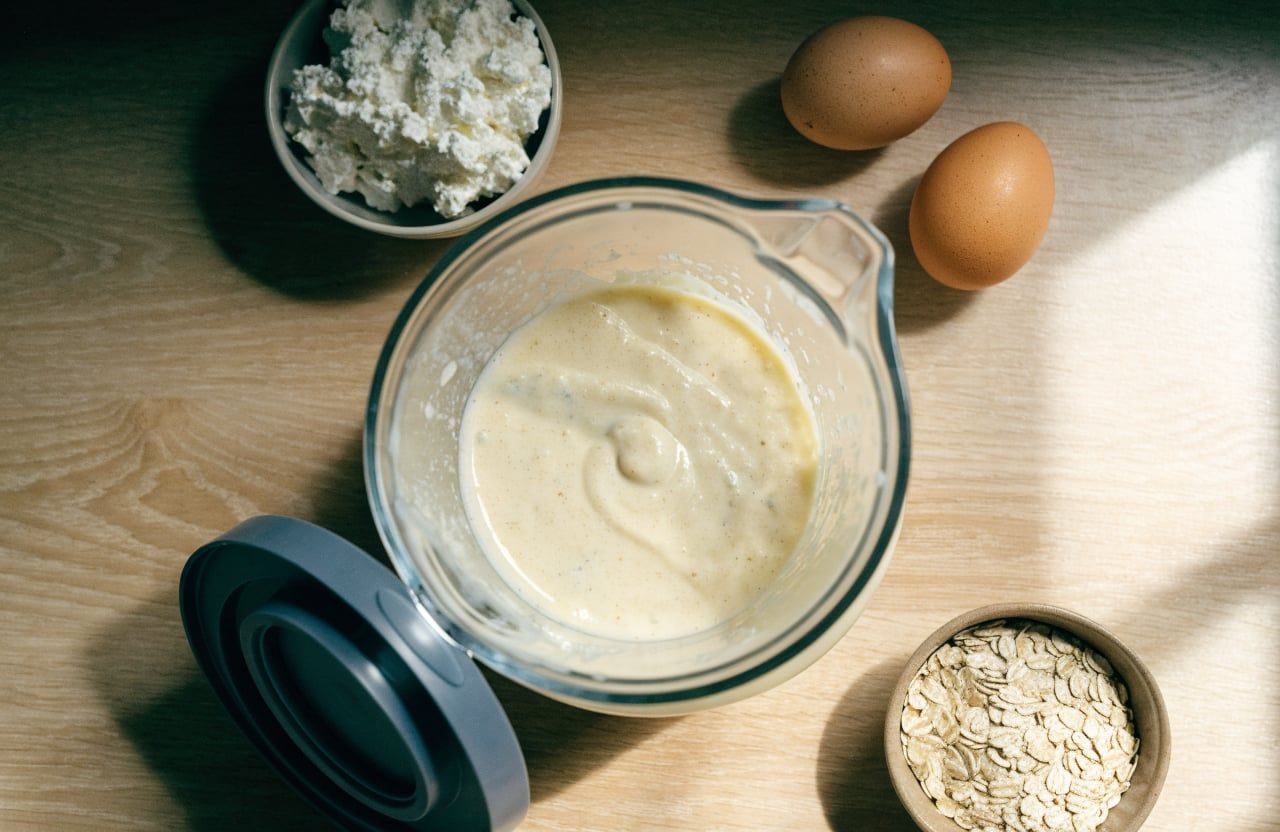 Blender jar filled with thick, smooth, pale cream pancake batter with tiny oat flecks
