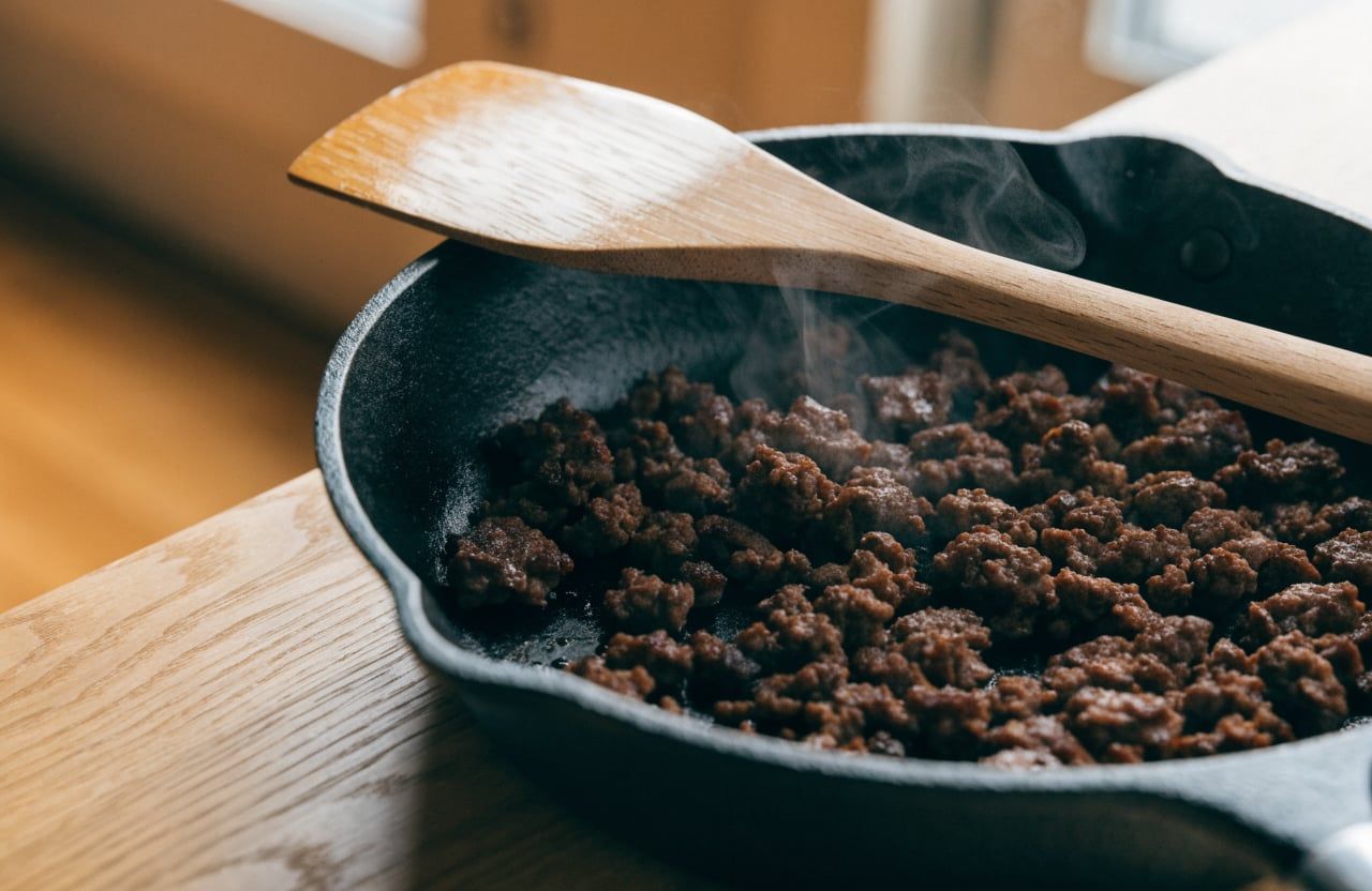 Ground beef browned into a deep brown crust in a skillet, partly broken into crumbles