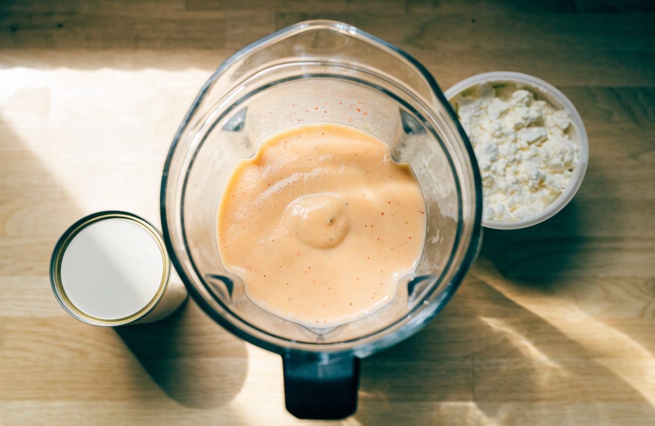 Blender jar of smooth pale peach cottage cheese sauce with no visible curds