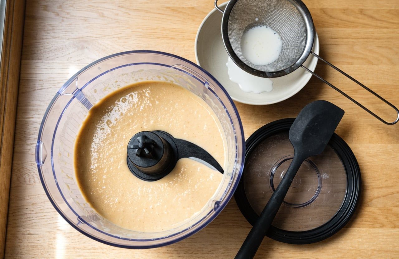 Food processor bowl with smooth, glossy, pale tan cottage cheese and peanut butter base