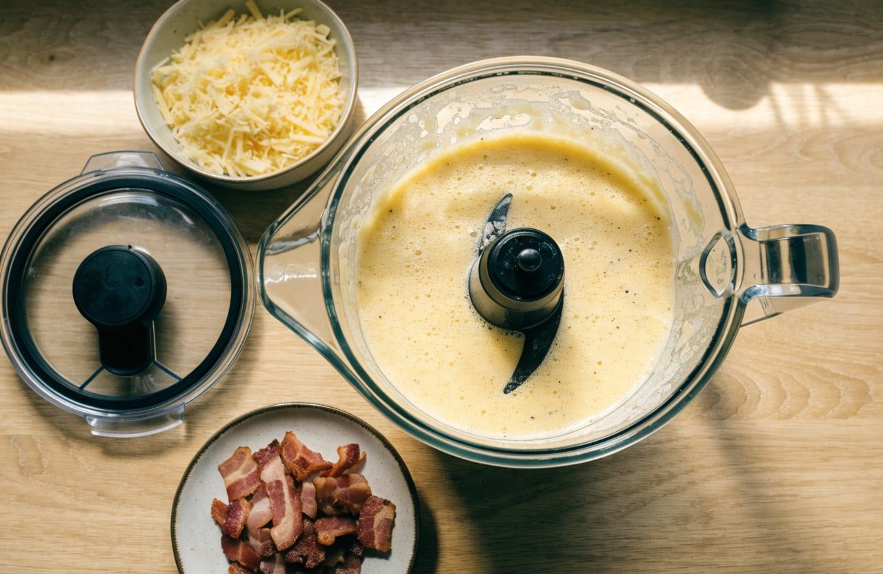 Blender jar filled with smooth, pale-yellow egg and cottage cheese batter with light froth on top