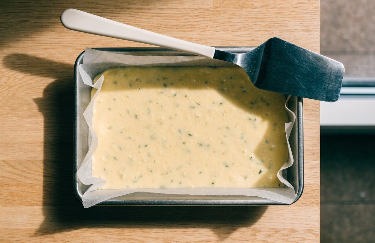 Thin pale-yellow batter spread in an even rectangle on parchment in a baking pan