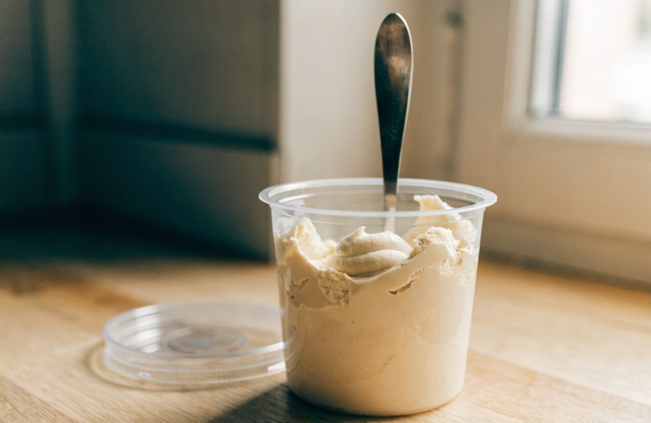 Open pint container of creamy pale ice cream with soft swirls after the re-spin