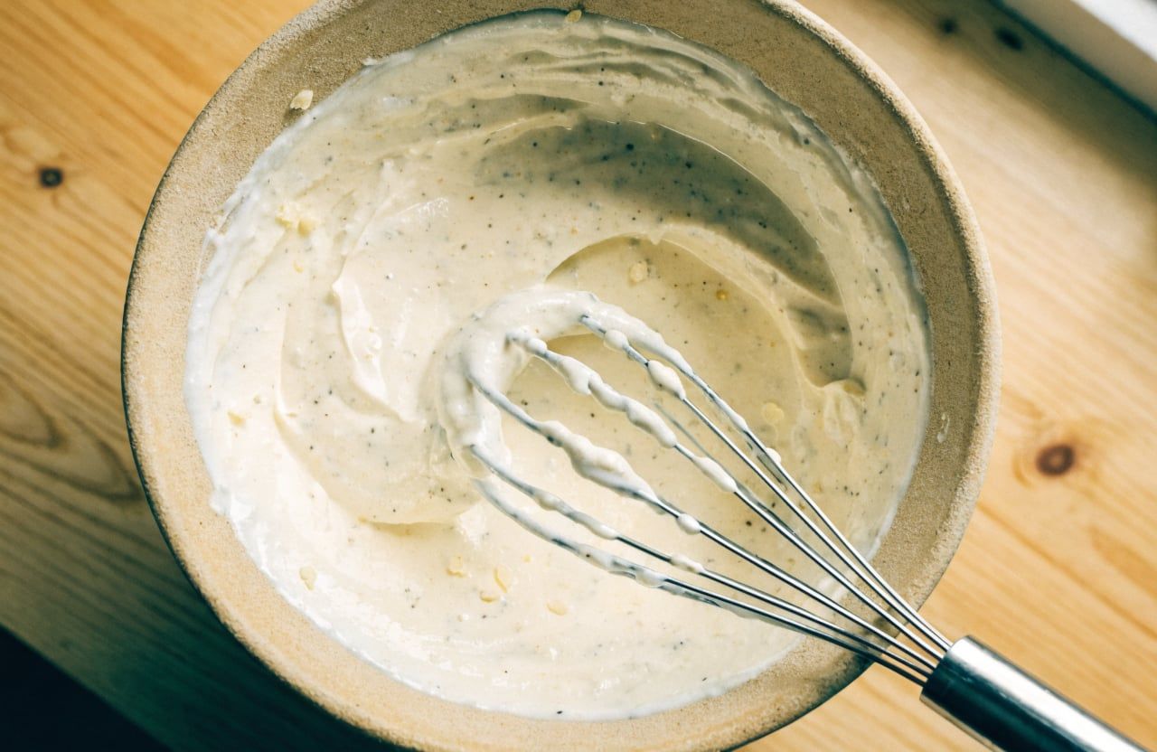 Thick creamy Greek yogurt Caesar dressing in a large bowl with a whisk