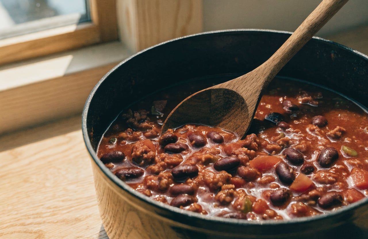 Thick simmered turkey chili with kidney beans in a Dutch oven, a spoon trail visible