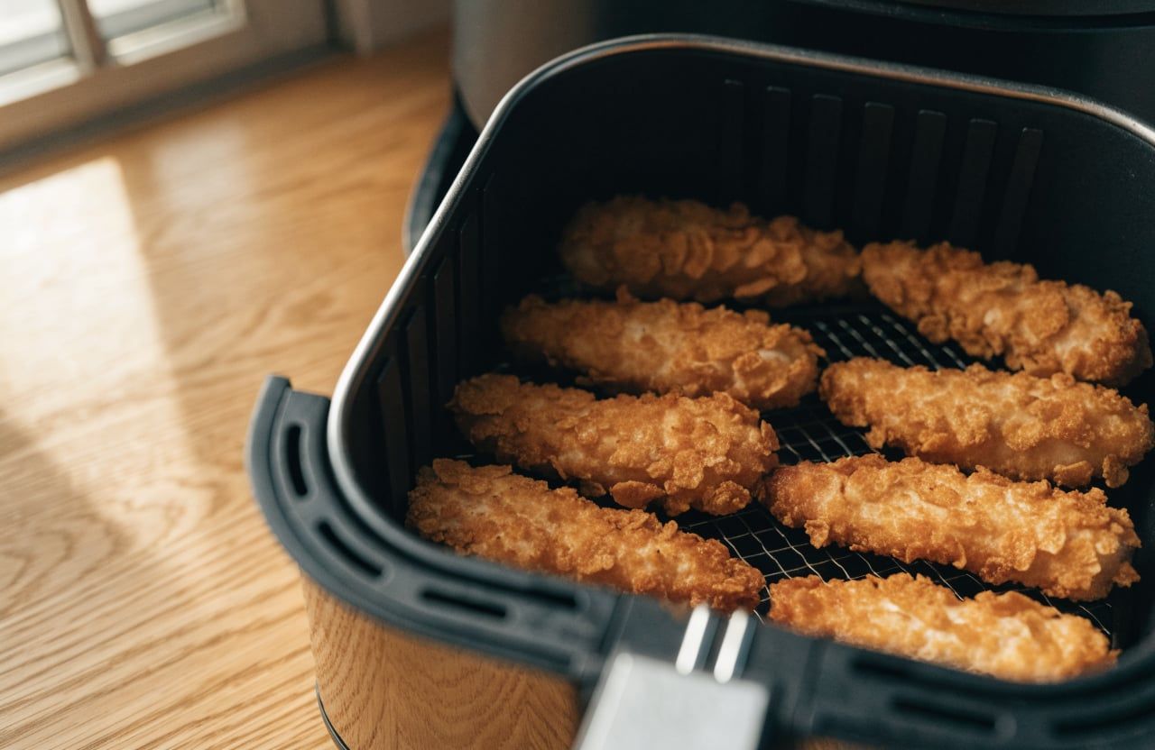 Crispy deep-golden chicken tenders in a single layer in an air fryer basket