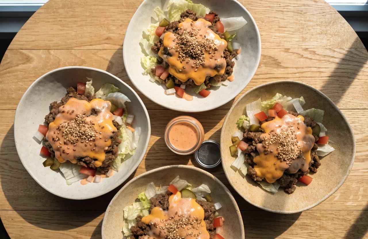Four bowls of iceberg, cheesy beef, tomato, pickles and onion drizzled with special sauce